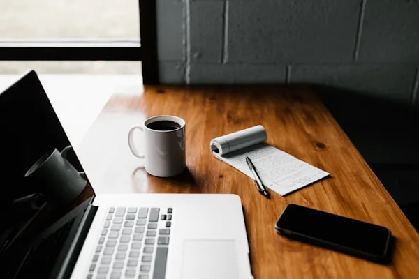 Escritorio ordenado con portátil, café y libreta