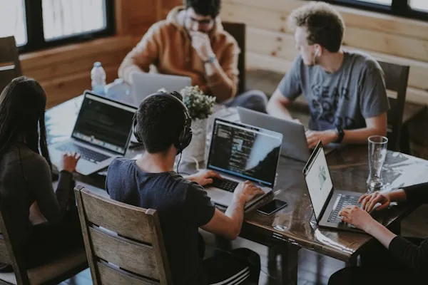 Equipo de trabajo colaborando en una mesa con portátiles